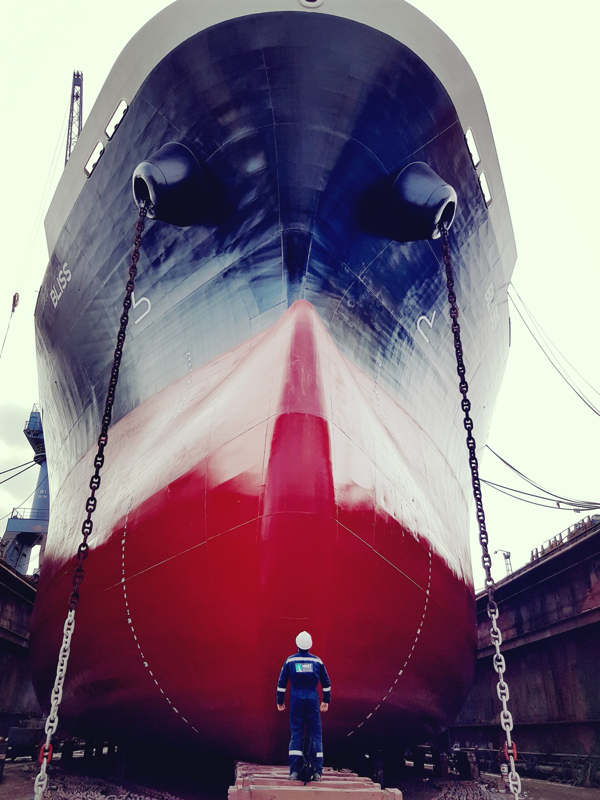 MAST engineer standing beneath a vessel's bow in drydock